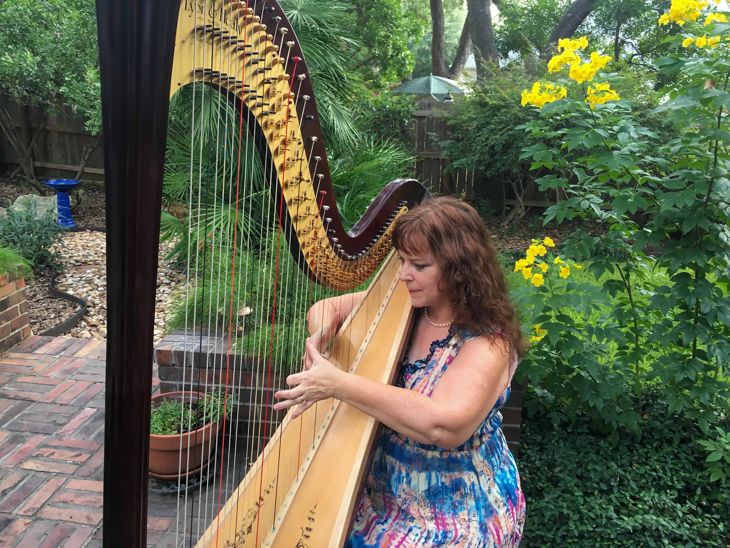 Sherri Stricker playing harp in a garden